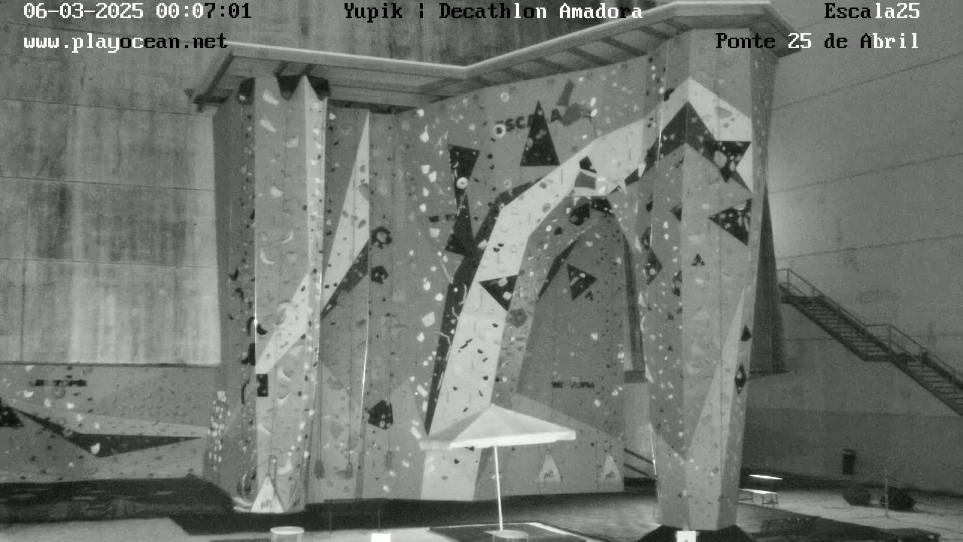 A large indoor climbing wall with various holds and patterns is shown in a grayscale image.