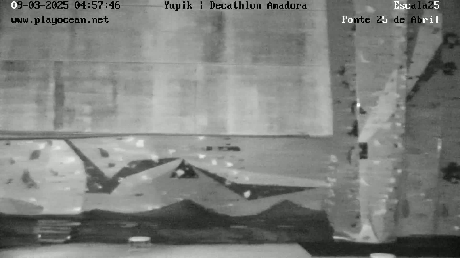 A grayscale image shows a portion of an indoor climbing wall with various holds, and a small part of a table is visible in the foreground.