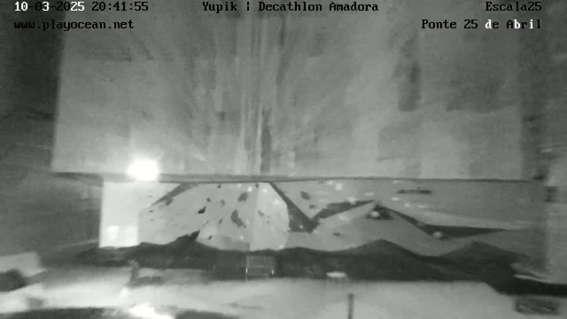 A nighttime, grainy black and white image shows an indoor climbing wall.