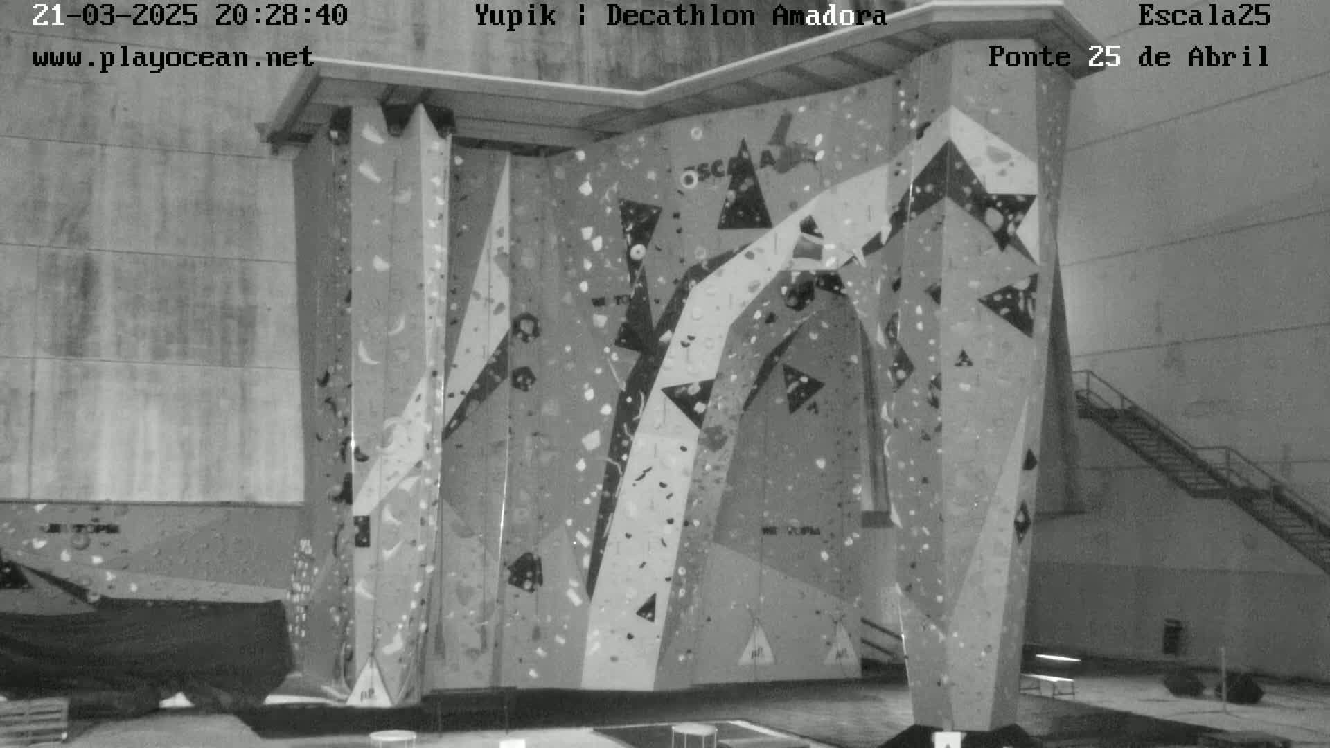 A grayscale image shows an indoor climbing wall with various holds and patterns.