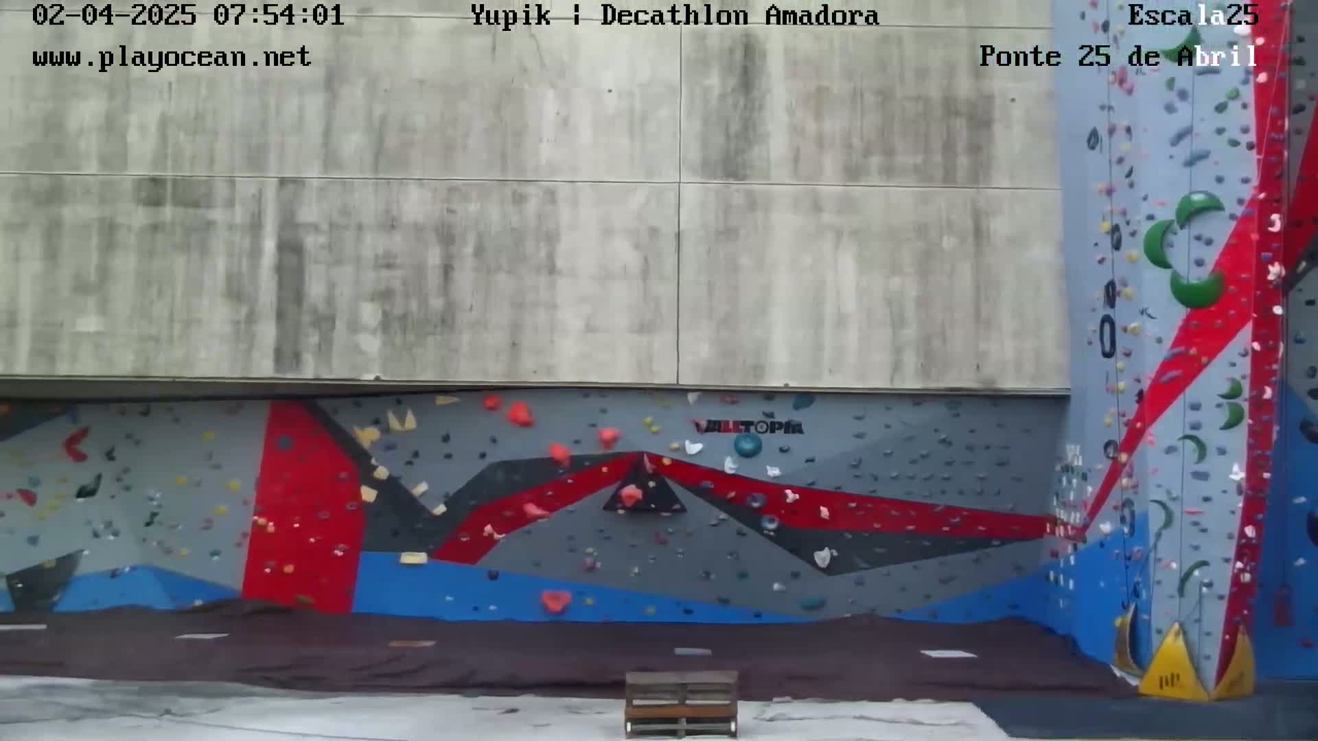 An outdoor view of a brightly colored climbing wall, under overcast skies.