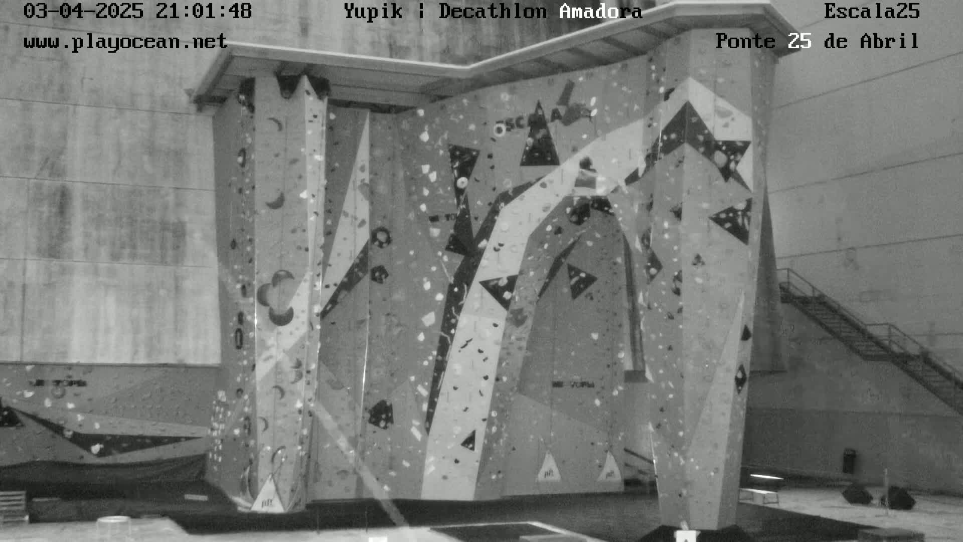 A grayscale image shows an indoor climbing wall with various holds and patterns.