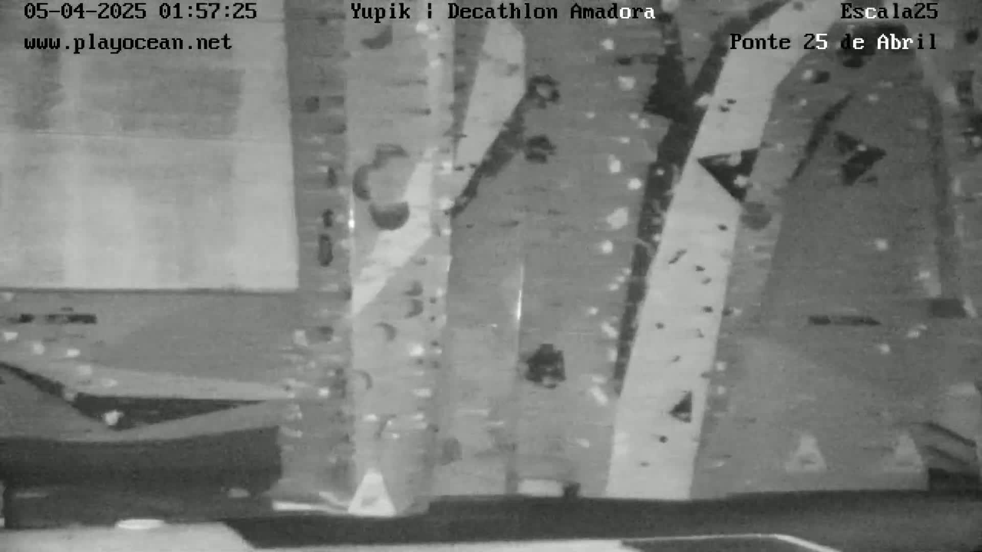 A grainy, black-and-white indoor image shows a wall with various shapes and patterns, covered in small specks that appear to be confetti.