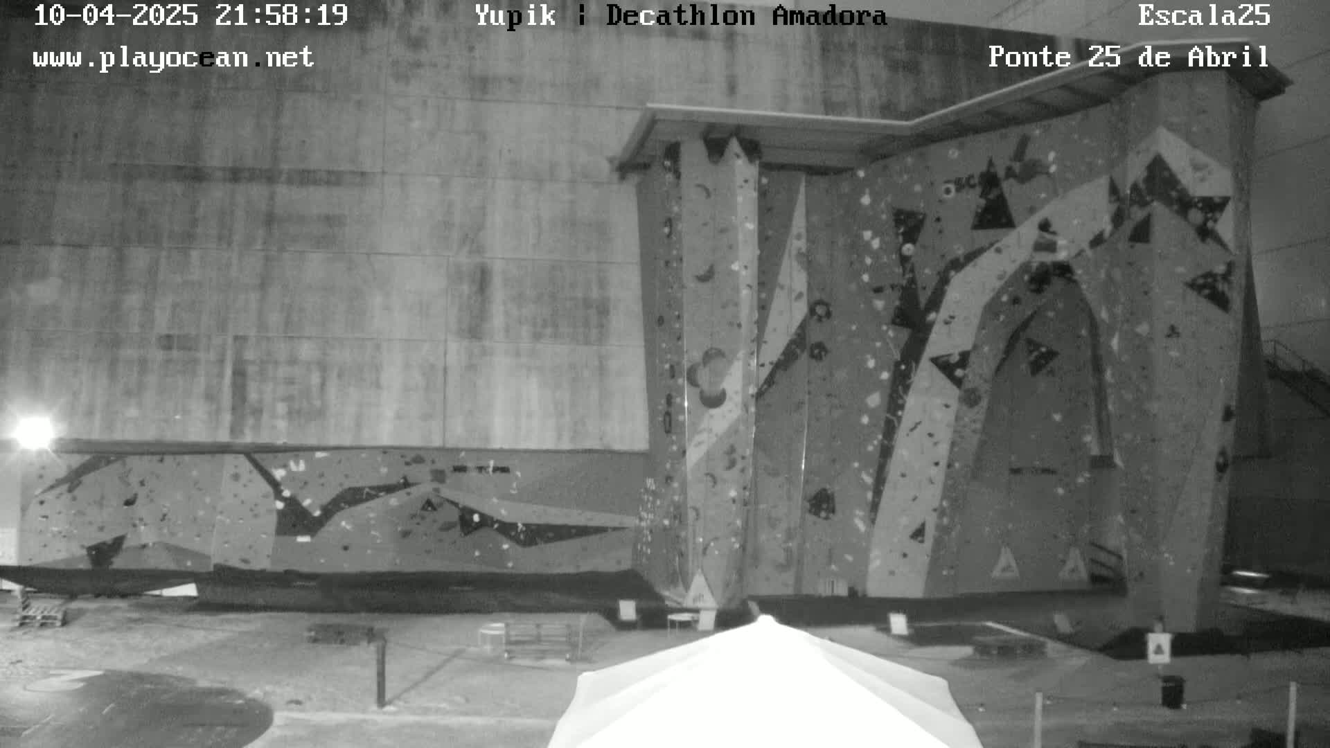 A large indoor climbing wall is illuminated at night.