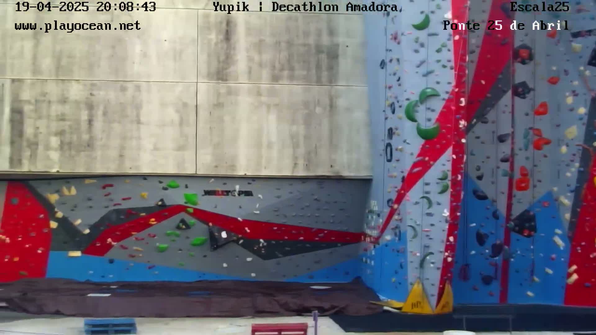 An outdoor, brightly colored climbing wall with various sized holds is shown in an image.