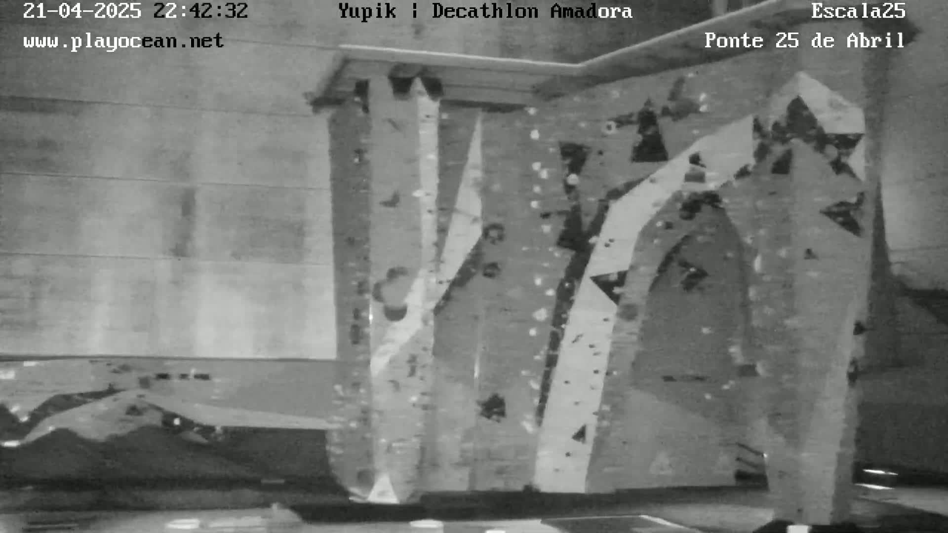 A grayscale image shows an indoor climbing wall with various handholds and footholds.