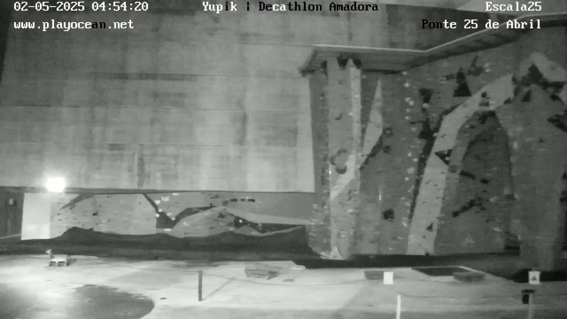 A nighttime, black-and-white view of an indoor rock climbing wall.
