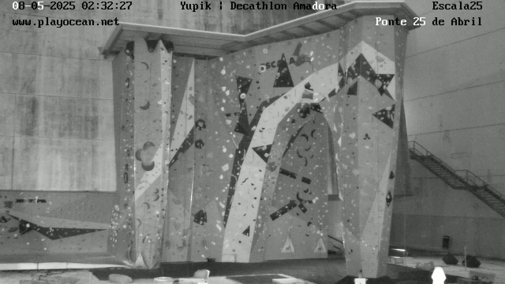 A large indoor climbing wall with various holds and patterns is shown in a grayscale image.