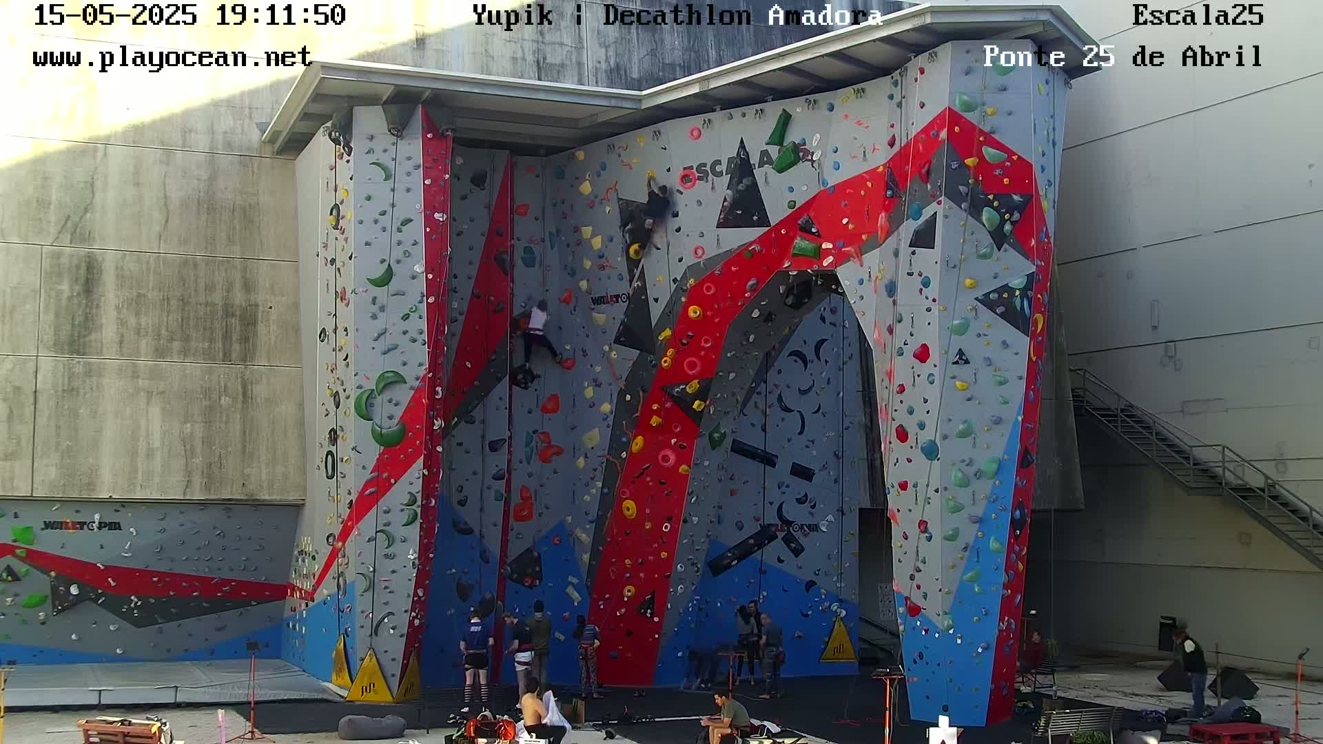 Several people are rock climbing on a large, brightly colored indoor climbing wall.