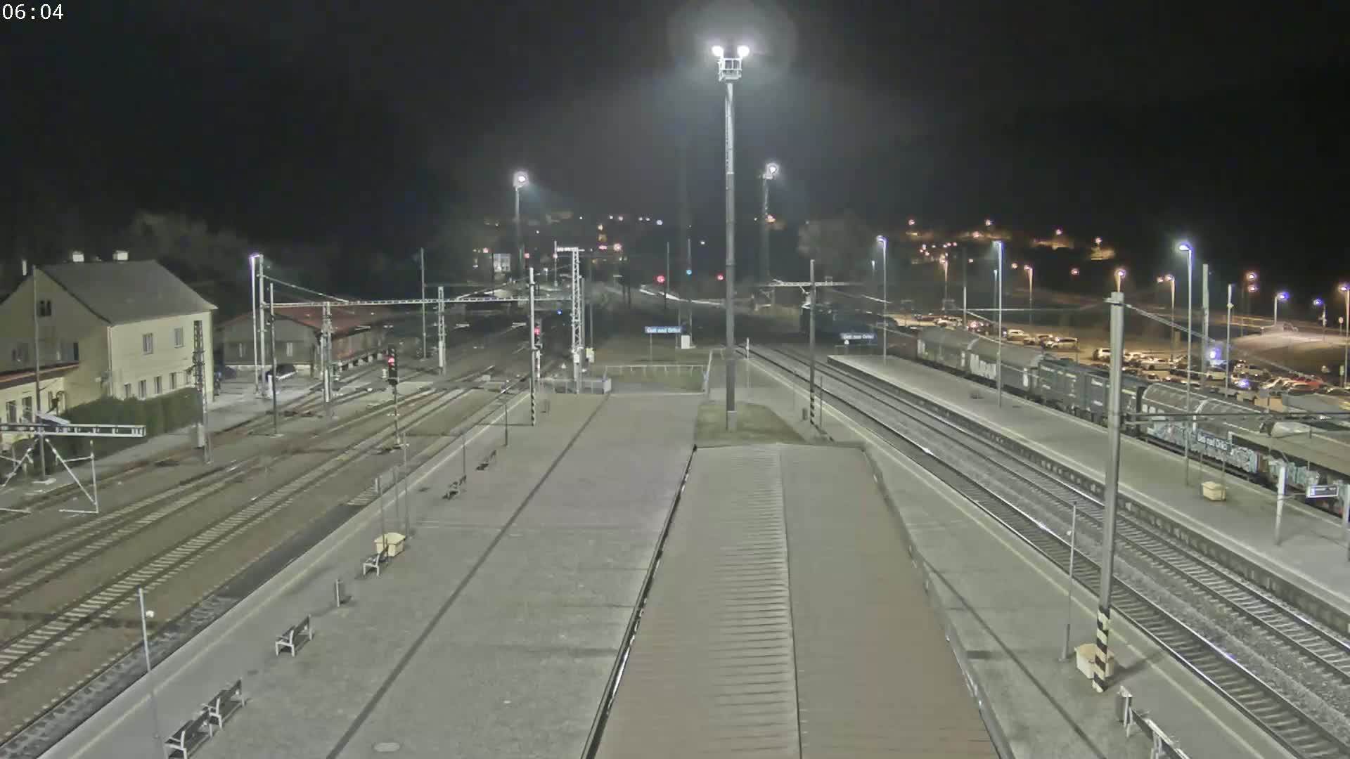 A nighttime view of a train station with several freight cars parked on the tracks, under clear skies.
