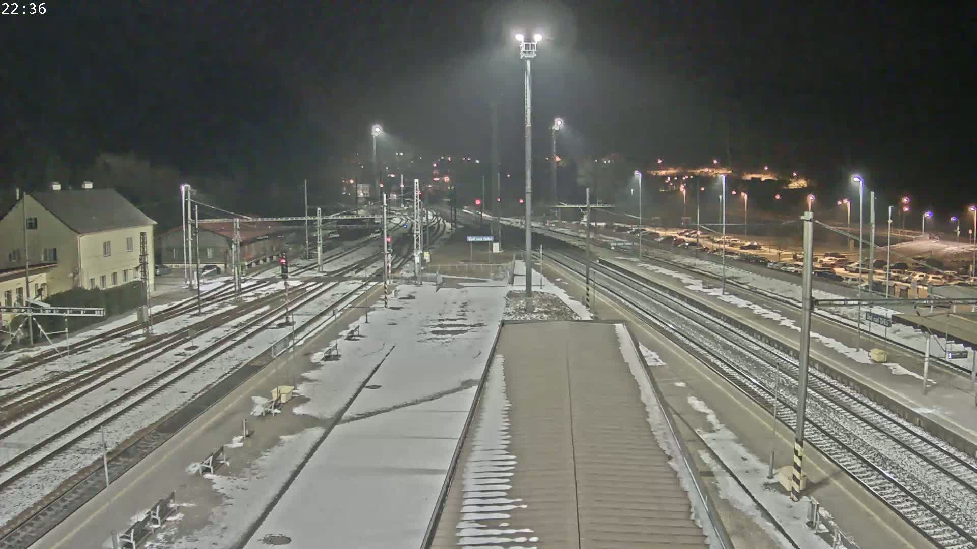 A snow-covered train station at night, illuminated by artificial lights.