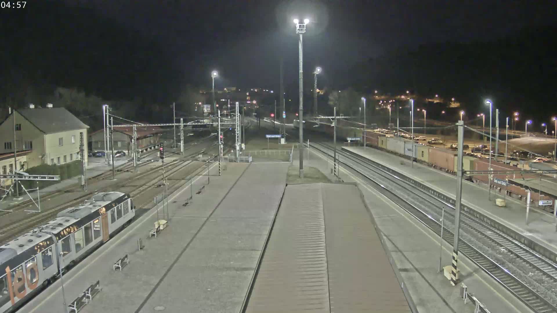 A nighttime view of a train station with a train at a platform and several rail lines, under clear skies.