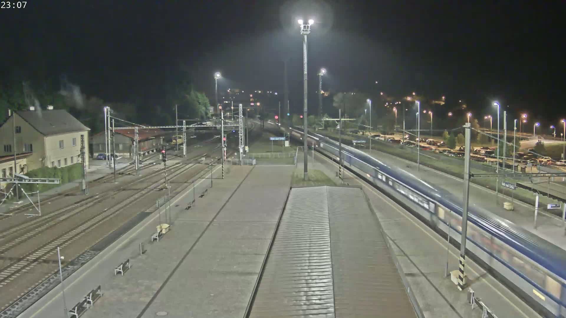 A long train passes through a train station at night.
