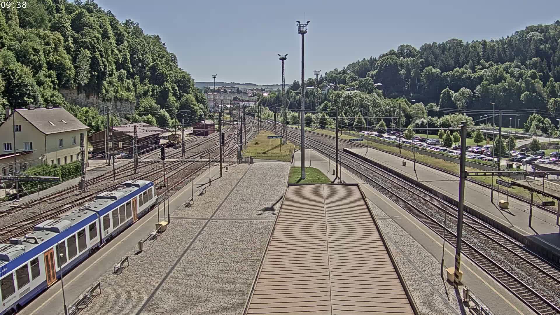 A train sits at a station next to several sets of train tracks under a clear sky.
