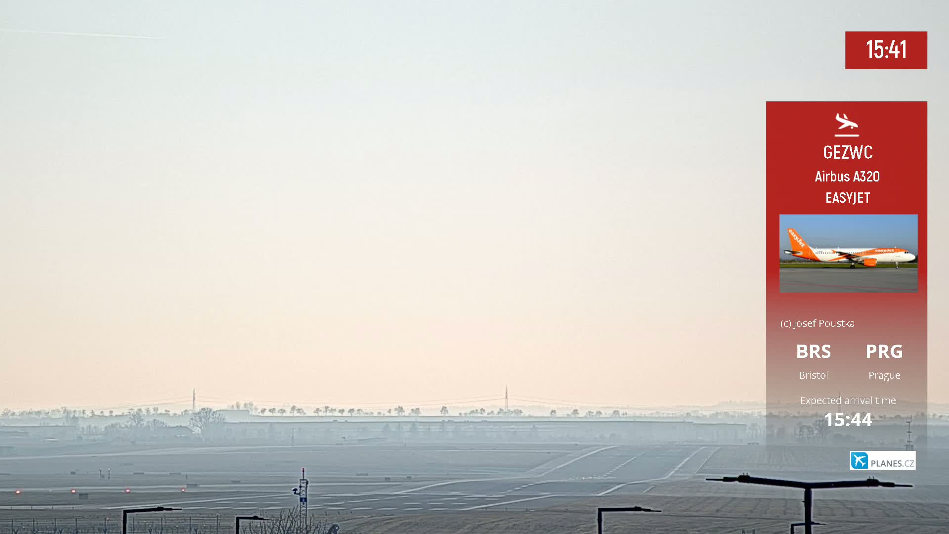 A hazy view of an airport runway with a plane approaching in the distance.