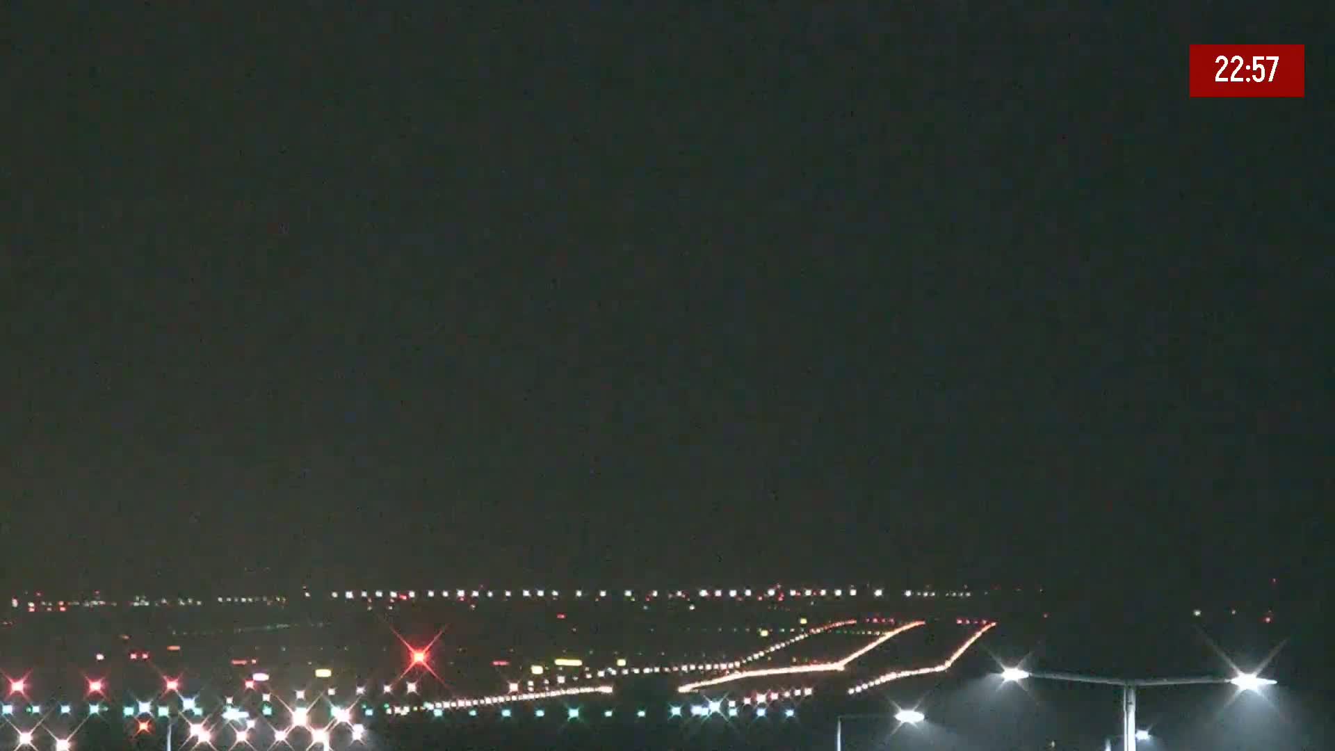 A nighttime view of an airport runway illuminated with lights under a dark sky.