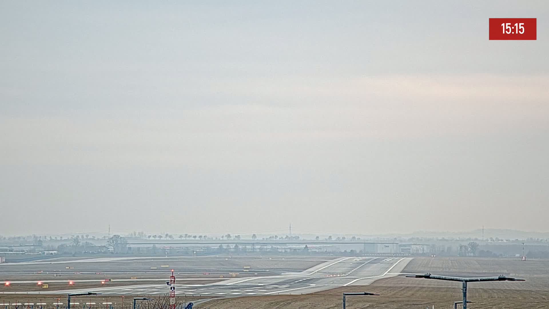 A hazy view of an airport runway, with low visibility and muted colors in the sky.