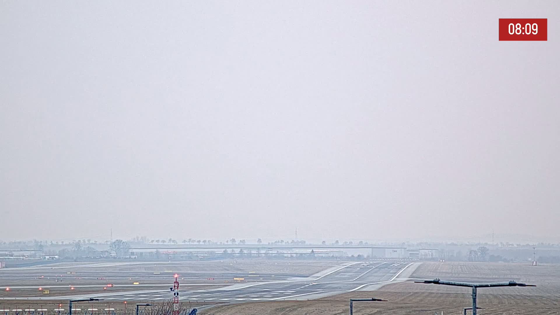 A hazy, overcast view of an airport runway and surrounding land.