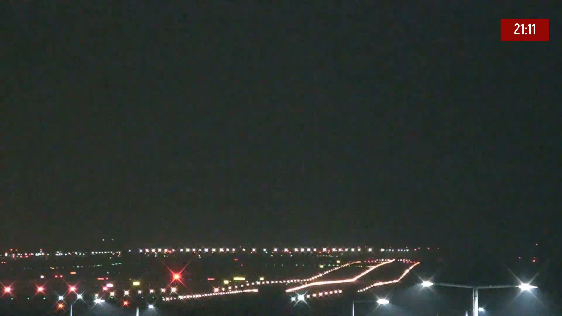 A nighttime view of a brightly lit airport runway under a dark, clear sky.