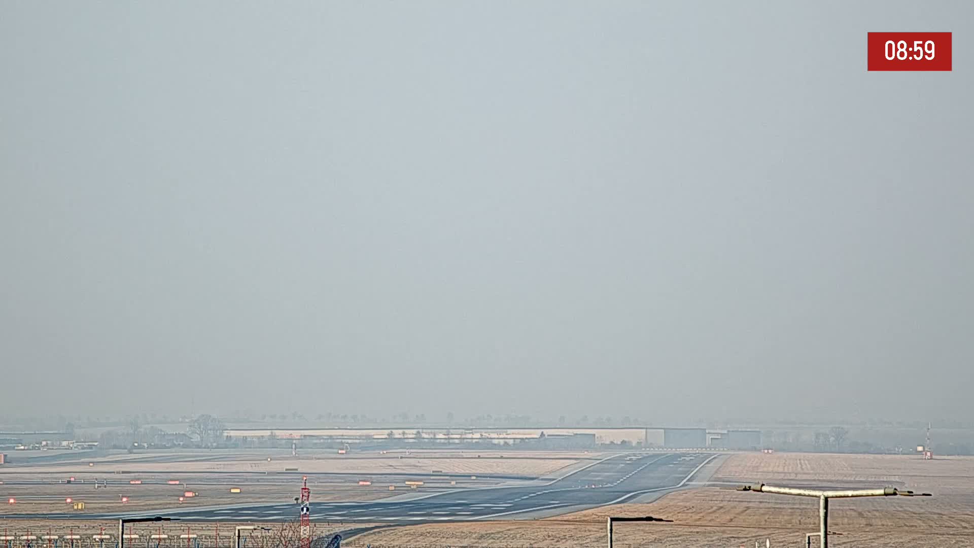A hazy view of an airport runway and surrounding flat land.