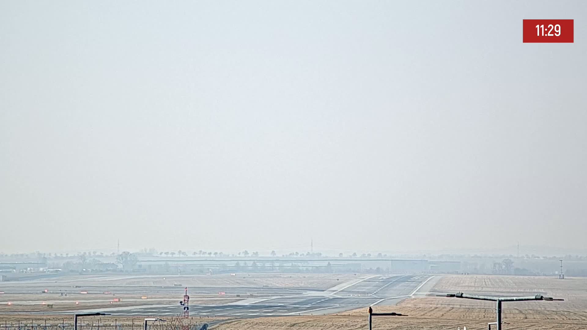 A hazy view of an airport runway and surrounding flat land.