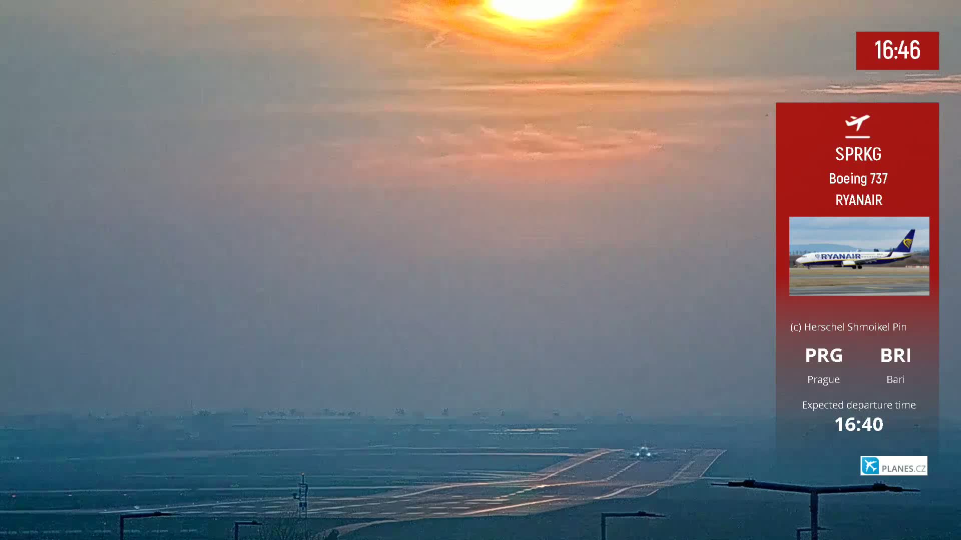 A hazy sunset over a long runway at an airport.