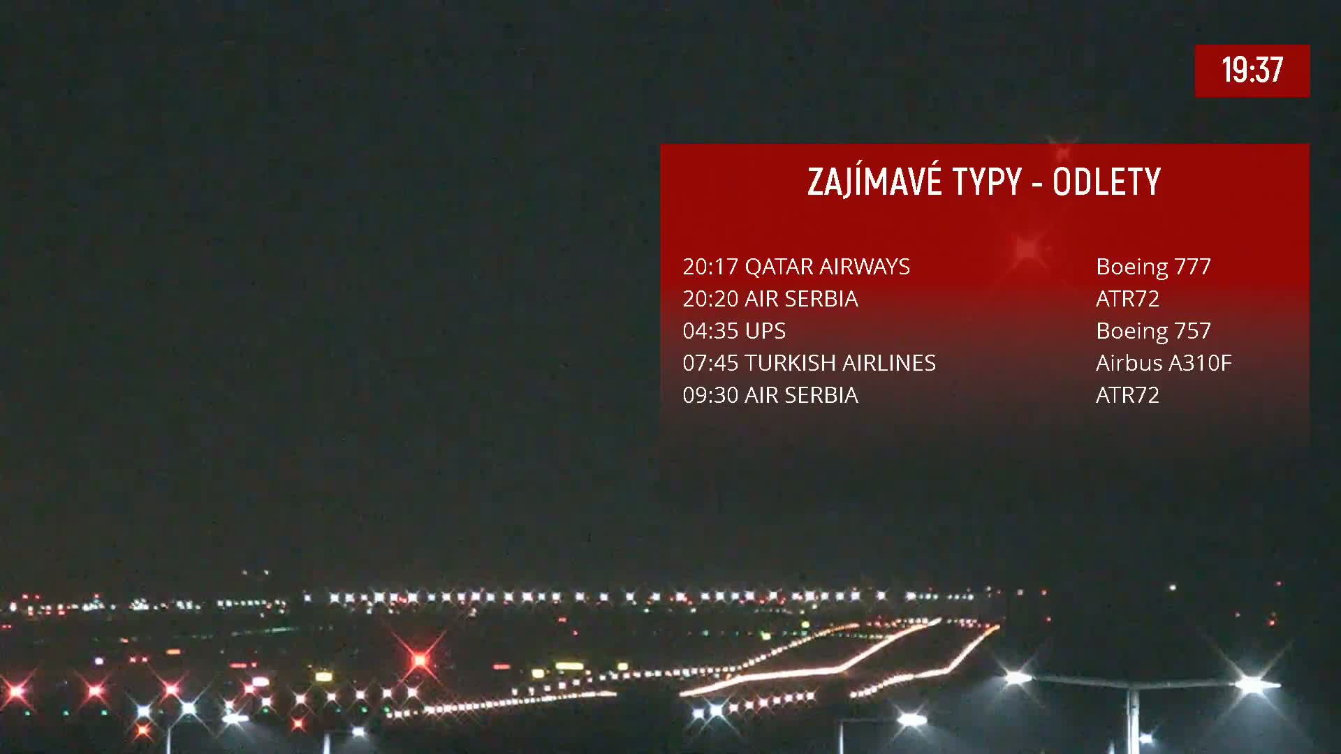 A nighttime view of an airport runway illuminated with lights.
