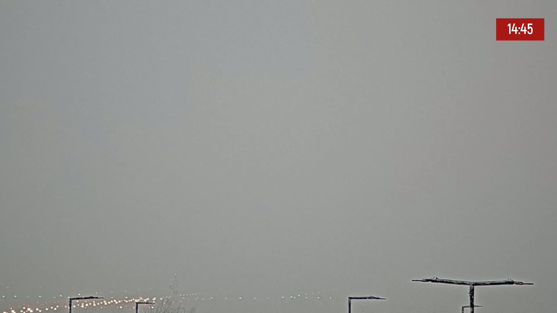 A hazy, overcast sky obscures a distant highway with visible taillights and a few trees at the bottom.