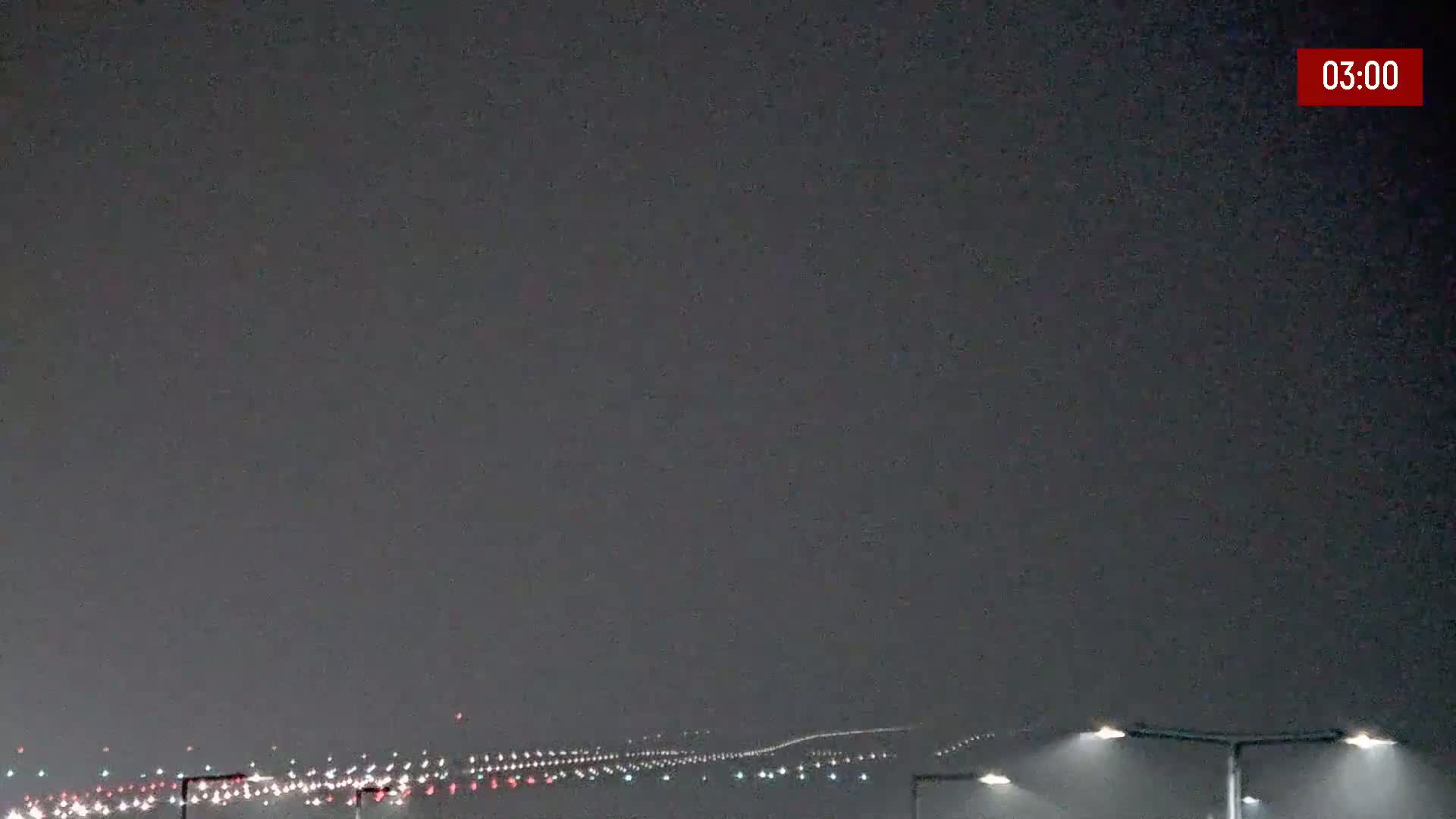 A nighttime, hazy view of a distant runway with its lights illuminated.