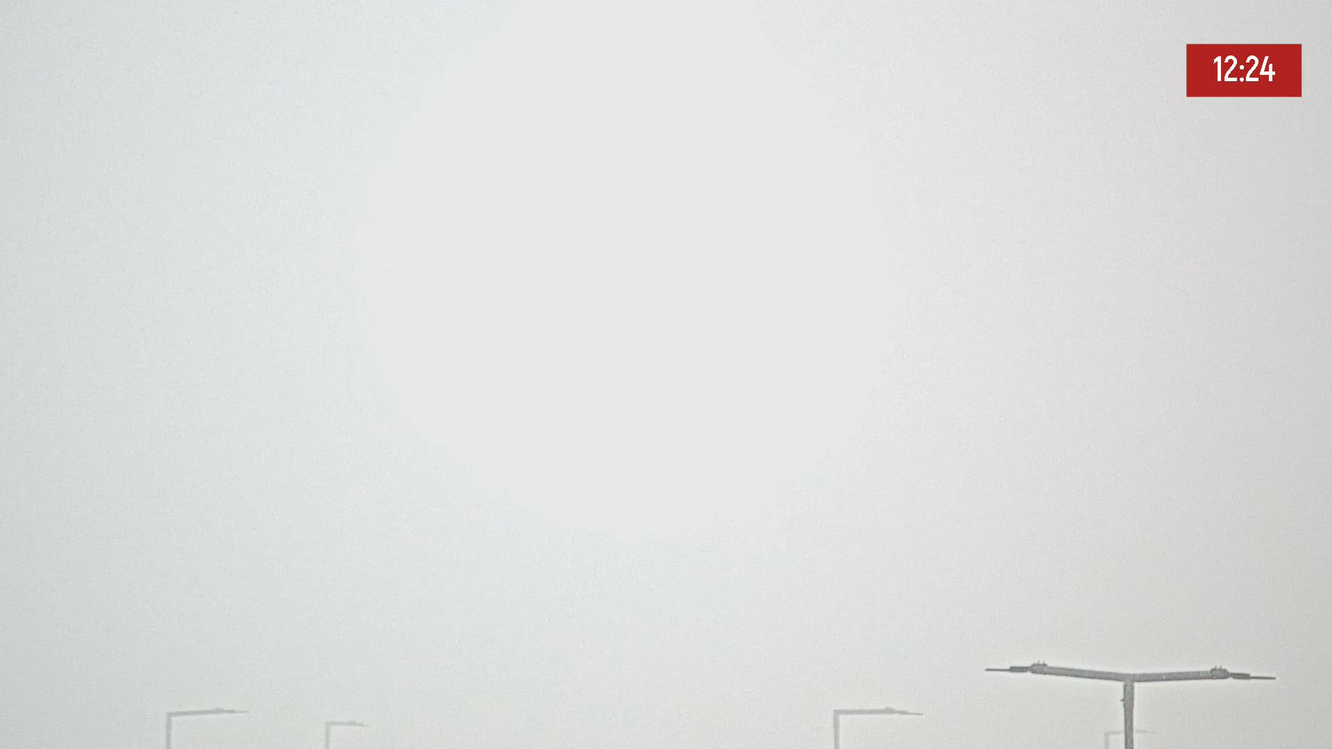 A foggy outdoor scene shows several lampposts against a very pale, hazy sky.