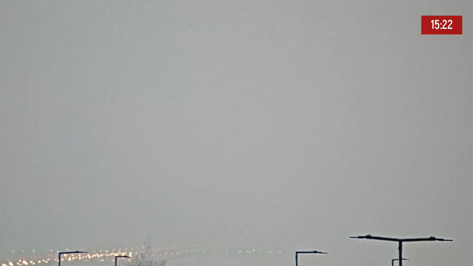 A hazy, snowy scene shows distant lights and a few lampposts in the foreground.