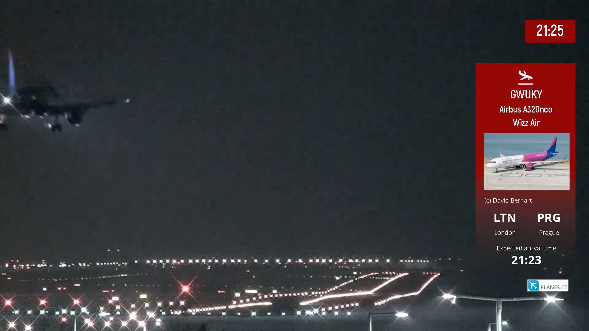 At night, an airplane is landing on a runway illuminated by lights.