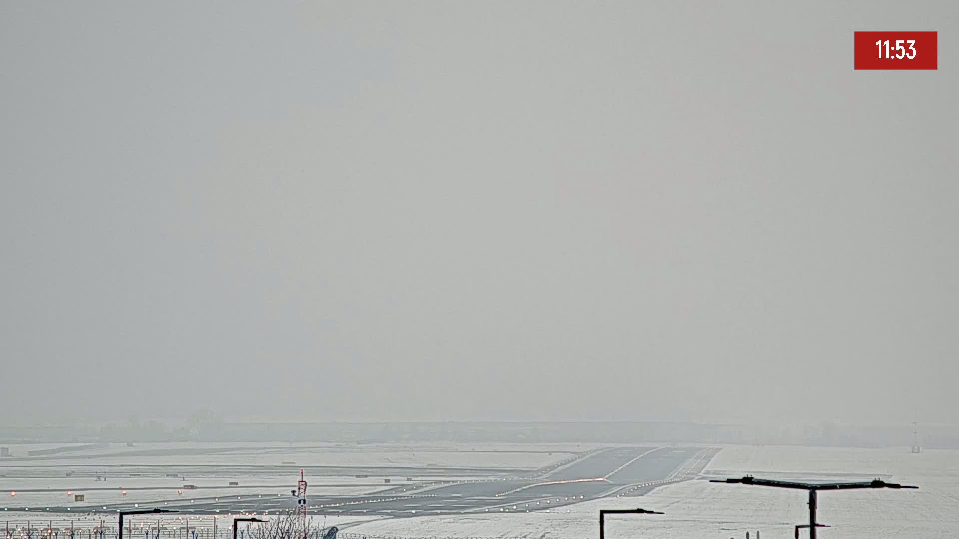 A snow-covered airport runway is visible under hazy, overcast conditions.