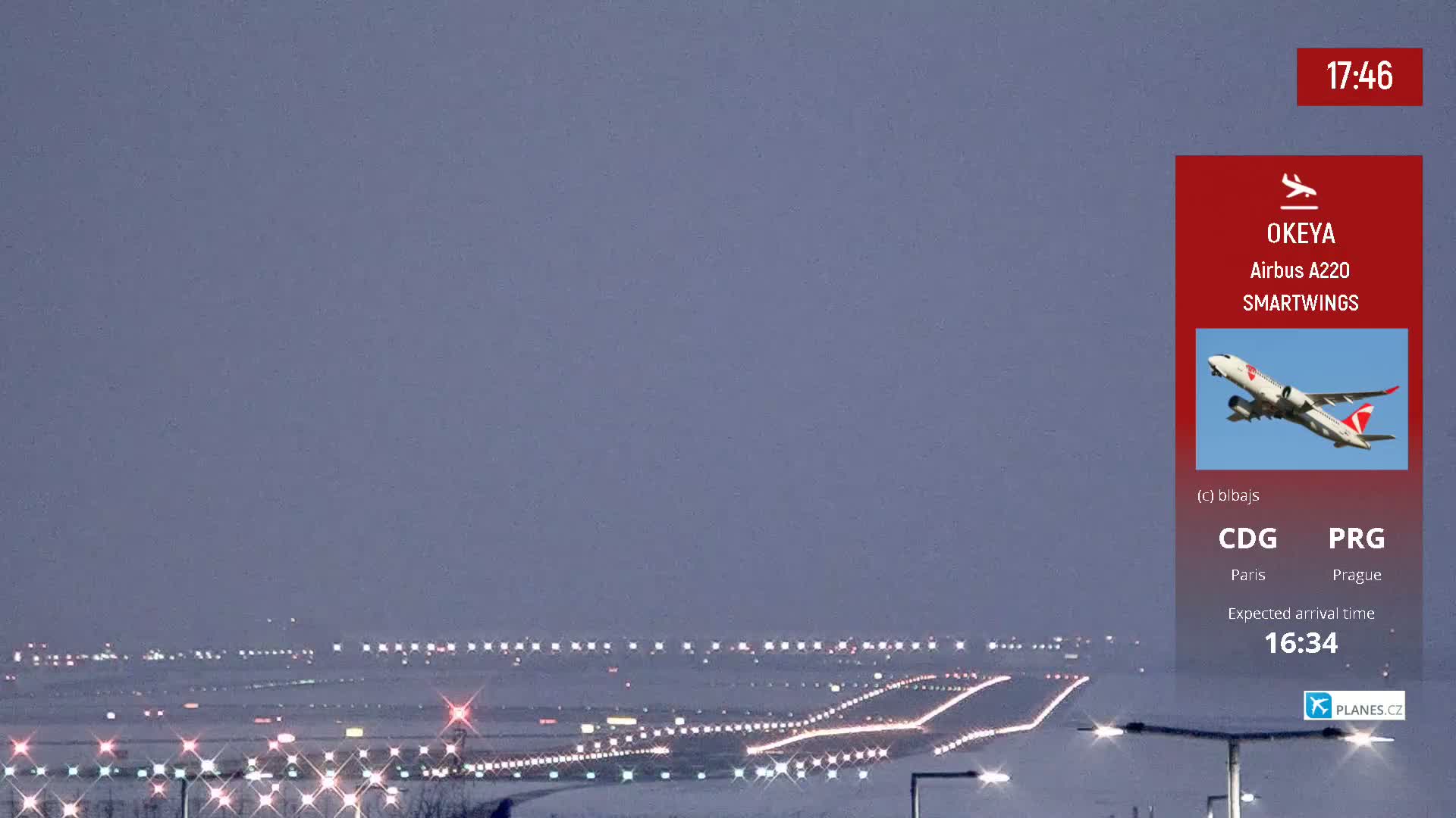 A snow-covered airport runway with lights illuminated under a dusky sky.