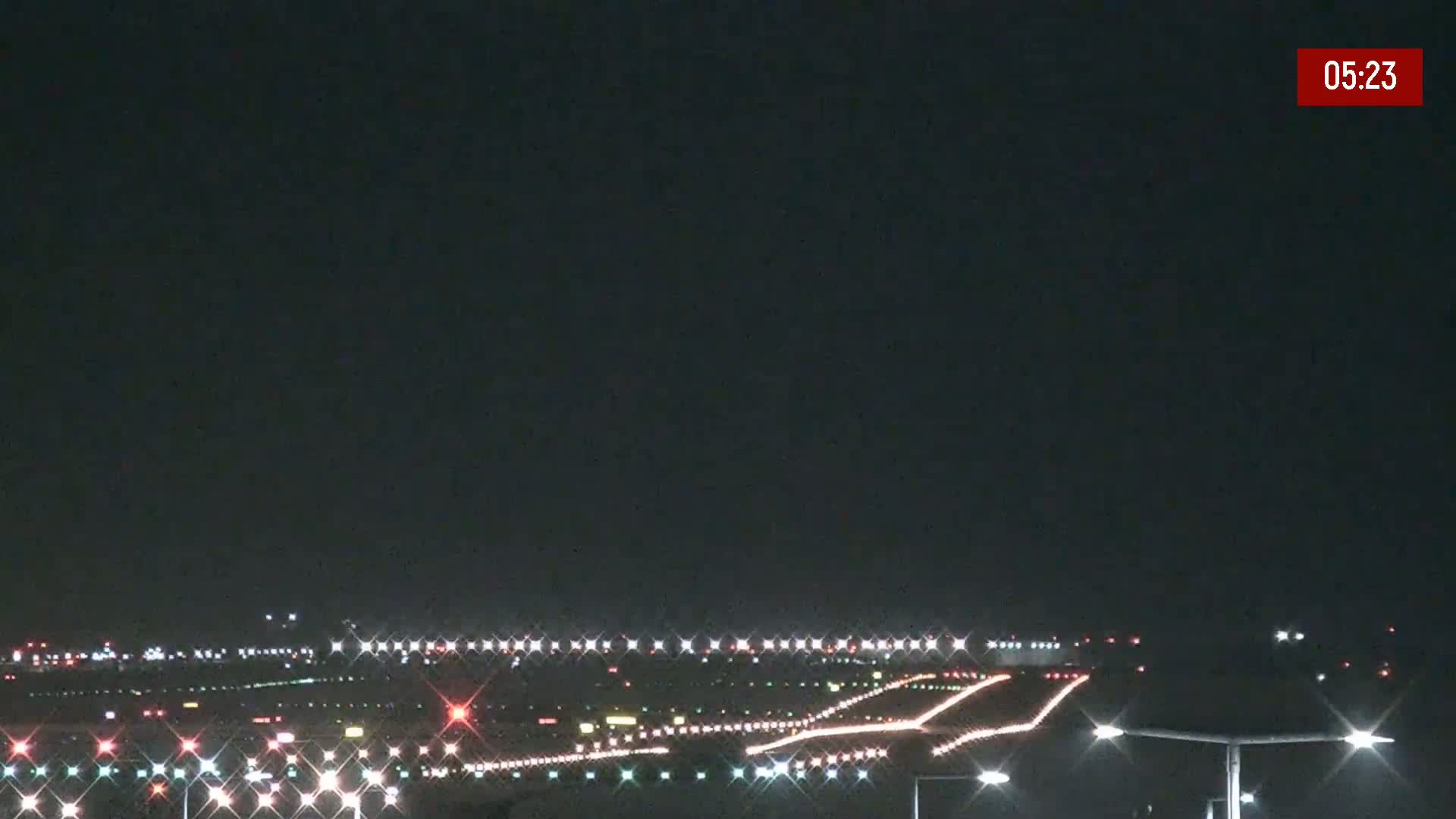 At night, an airport runway is illuminated with rows of lights.