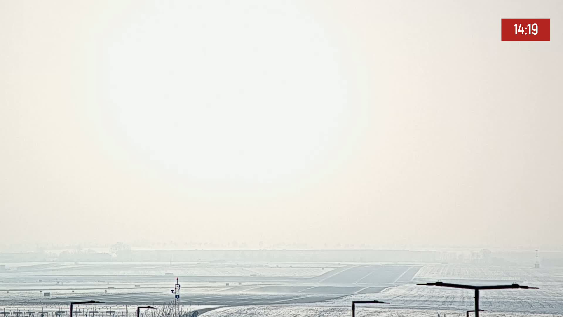 A hazy, snowy airfield is visible under a bright, overcast sky.