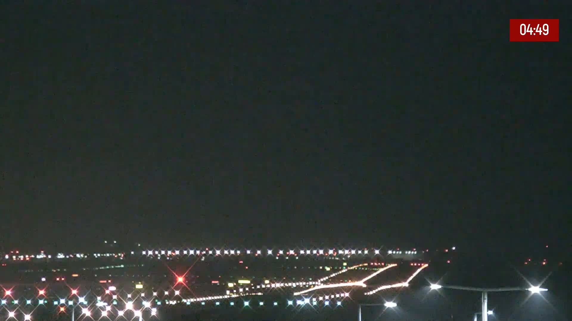 A nighttime long shot of an airport runway illuminated with lights under a dark, clear sky.