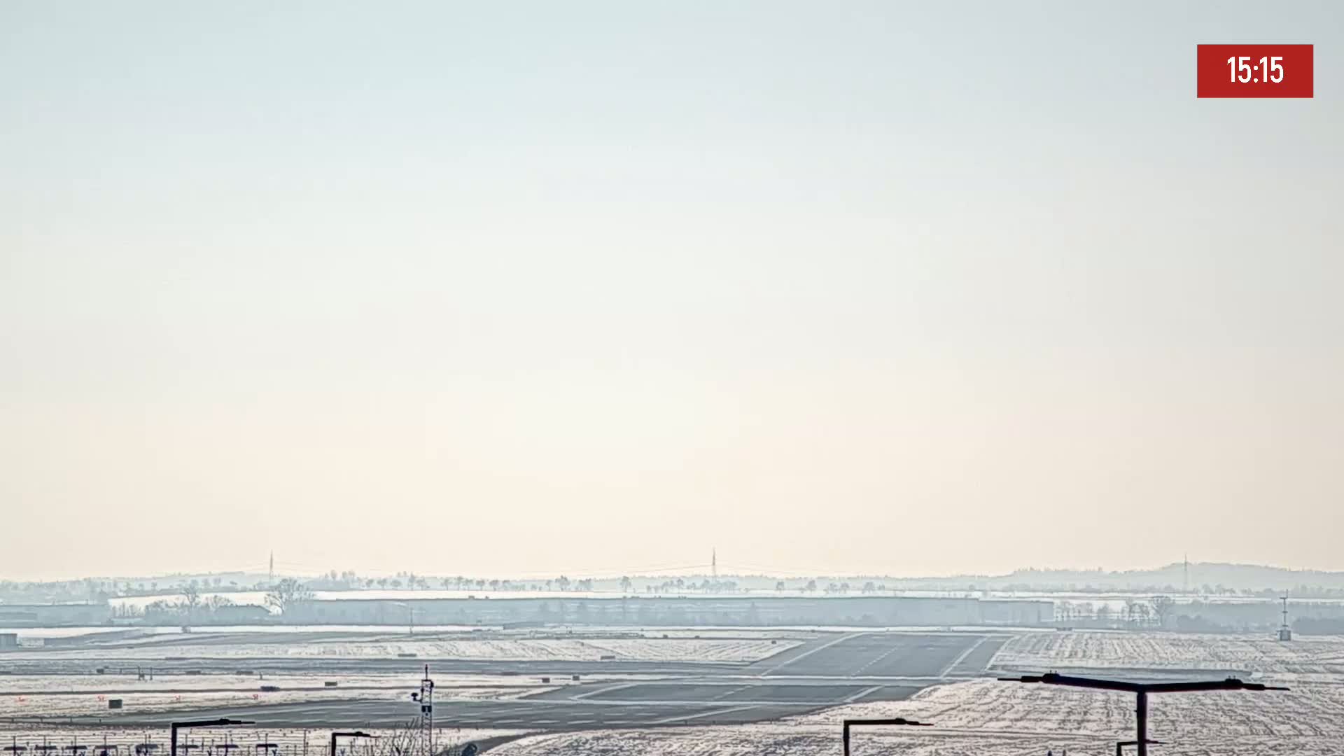 A hazy, snow-covered airfield is visible in the distance under a pale sky.
