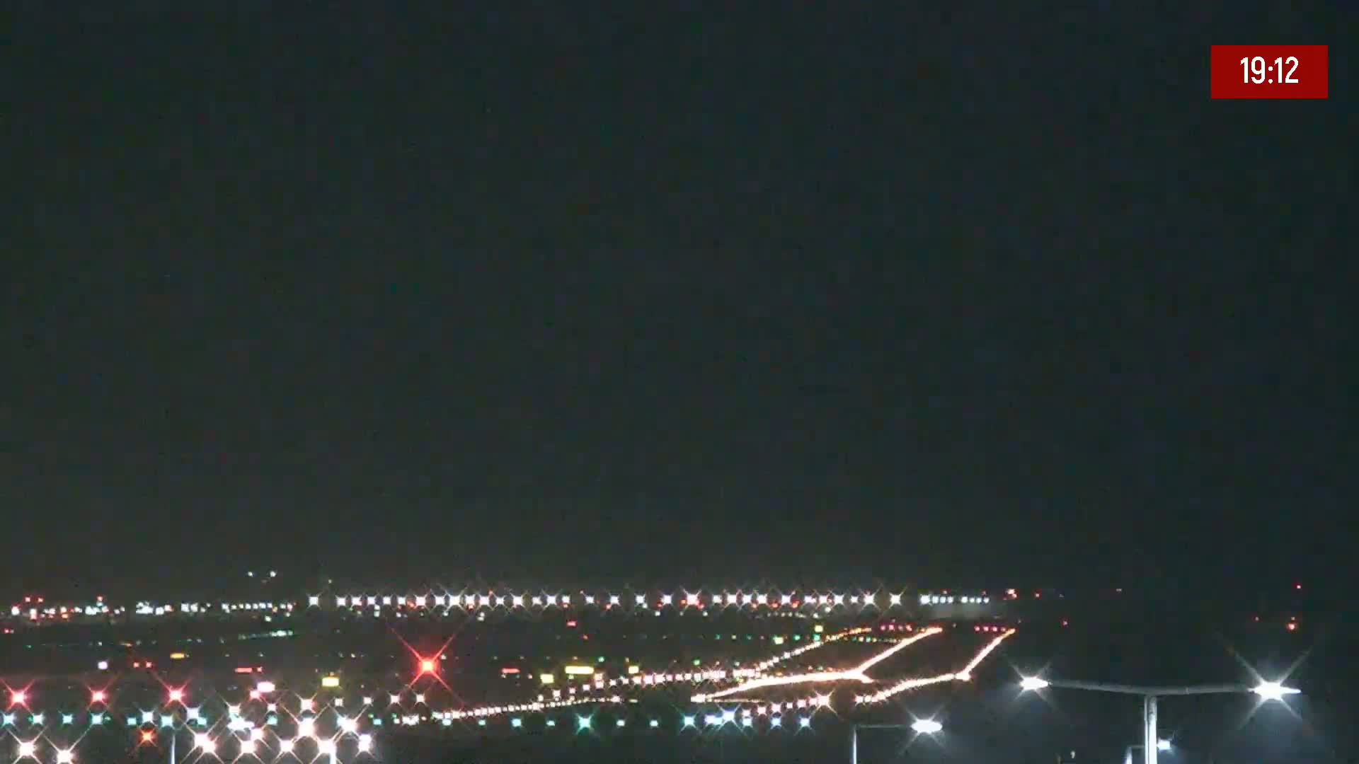 A nighttime view of a brightly lit airport runway and taxiways under a clear, dark sky.