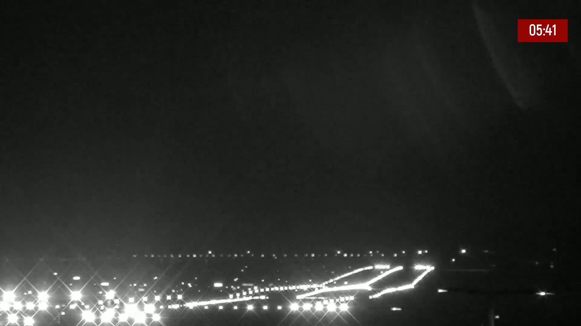 A nighttime, long shot of a highway with sparse traffic under a dark sky.