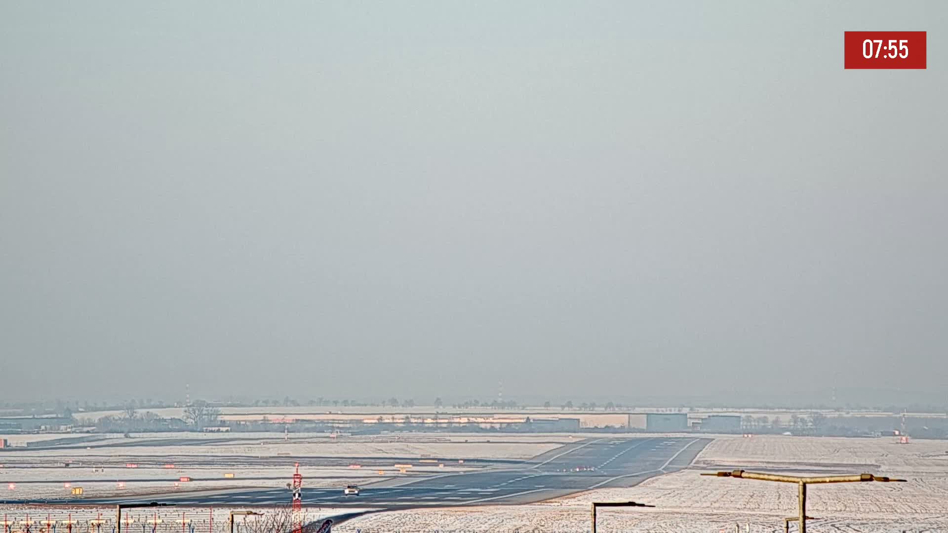 A snow-covered airport runway is visible under hazy conditions.