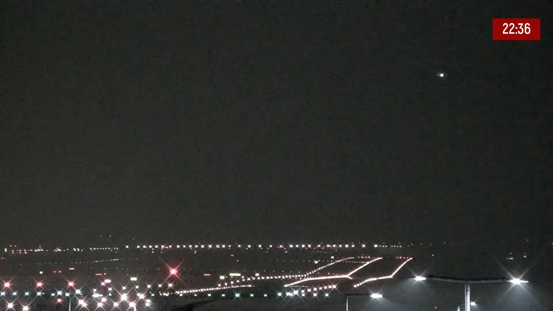 A nighttime view of an airport runway with lights illuminating the tarmac under a dark, clear sky.