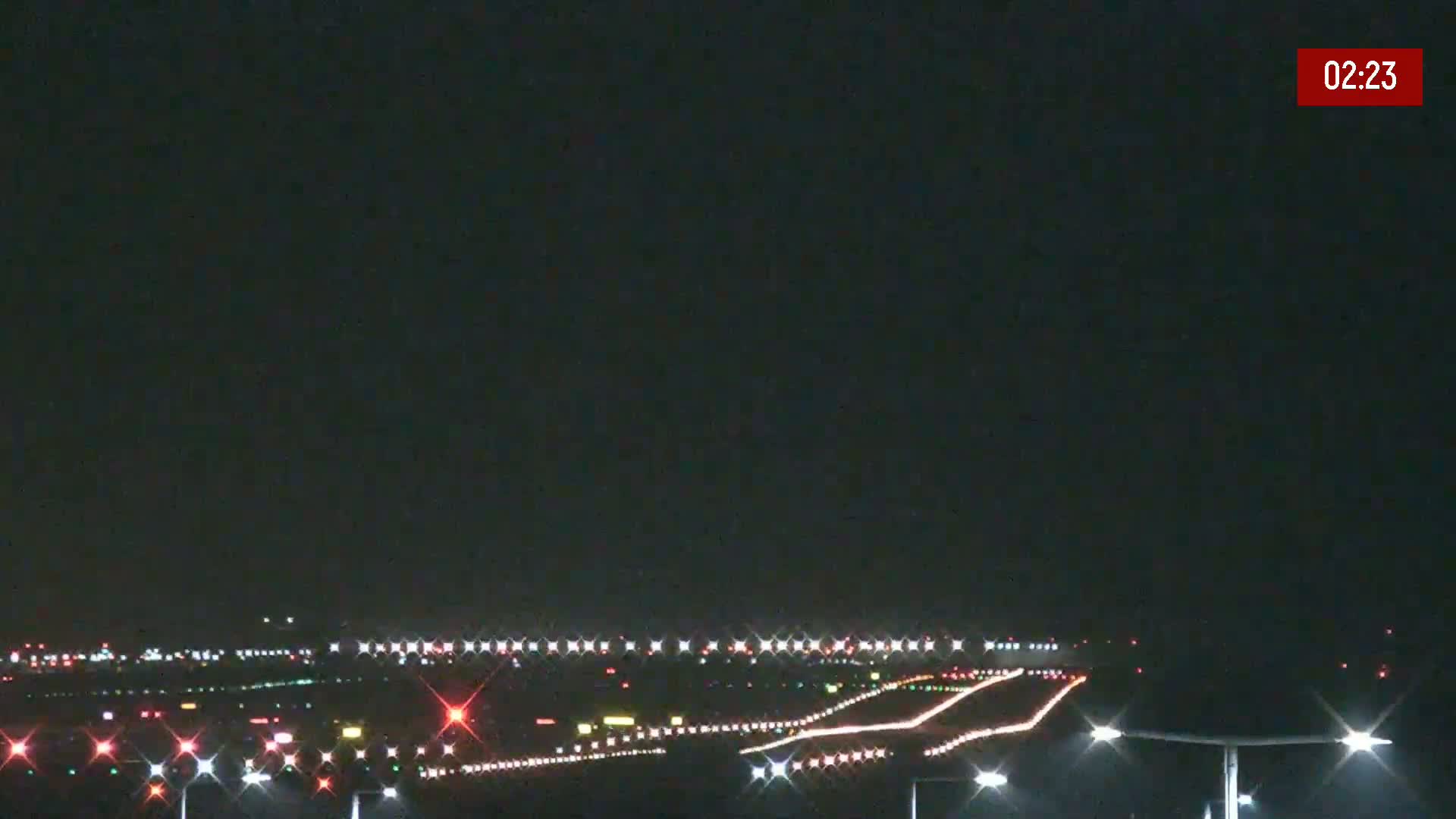 A nighttime view of an airport runway with lights illuminating the taxiways and surrounding area under a clear, dark sky.