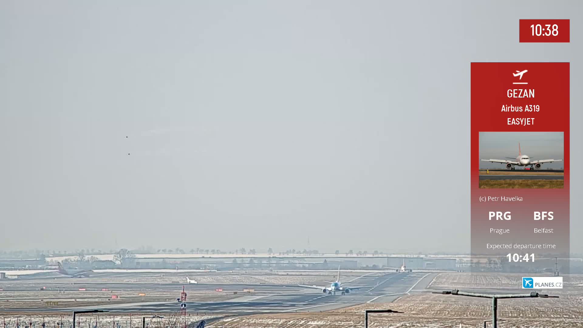A hazy, wintery airport scene shows several airplanes on the tarmac and runways, with one preparing for takeoff.