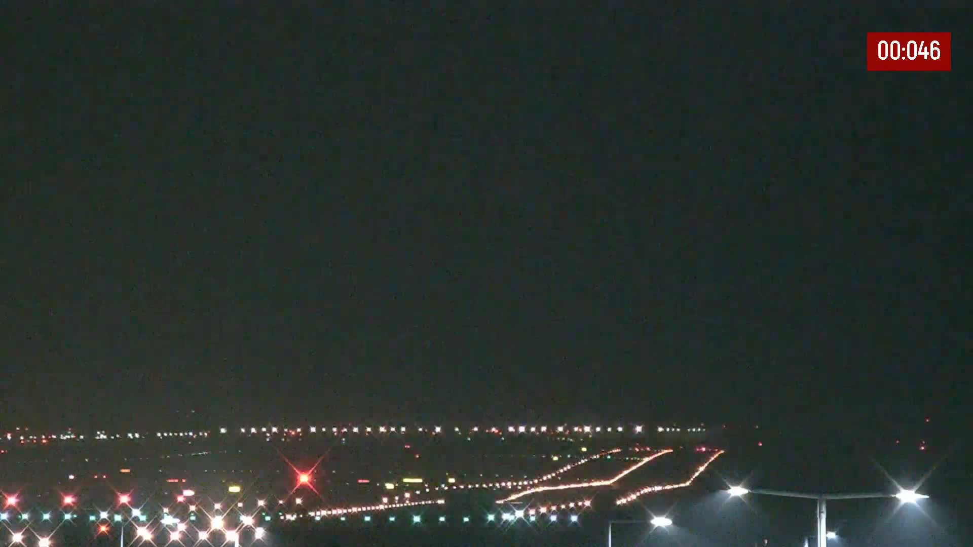 At night, the runway lights of an airport are illuminated under a clear, dark sky.