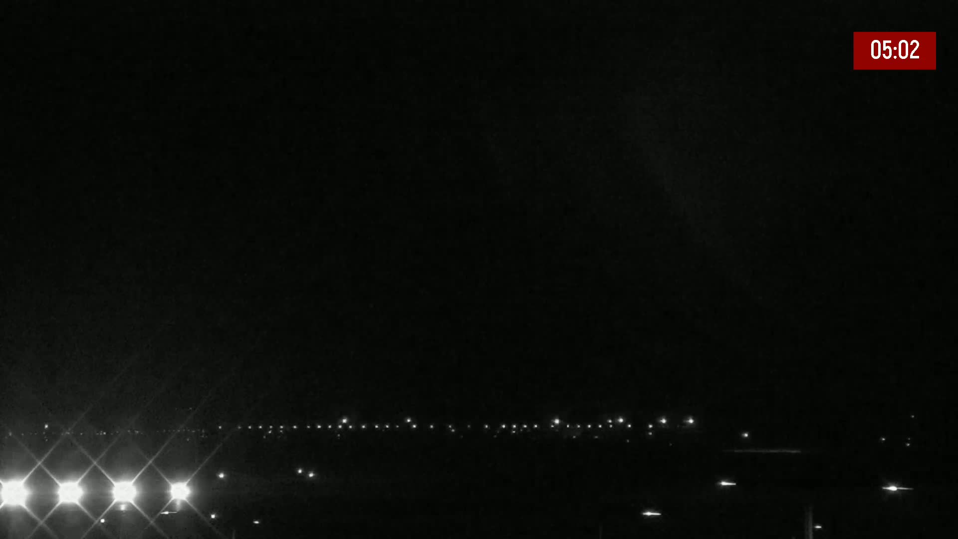 At night, a line of distant lights is visible against a dark sky.
