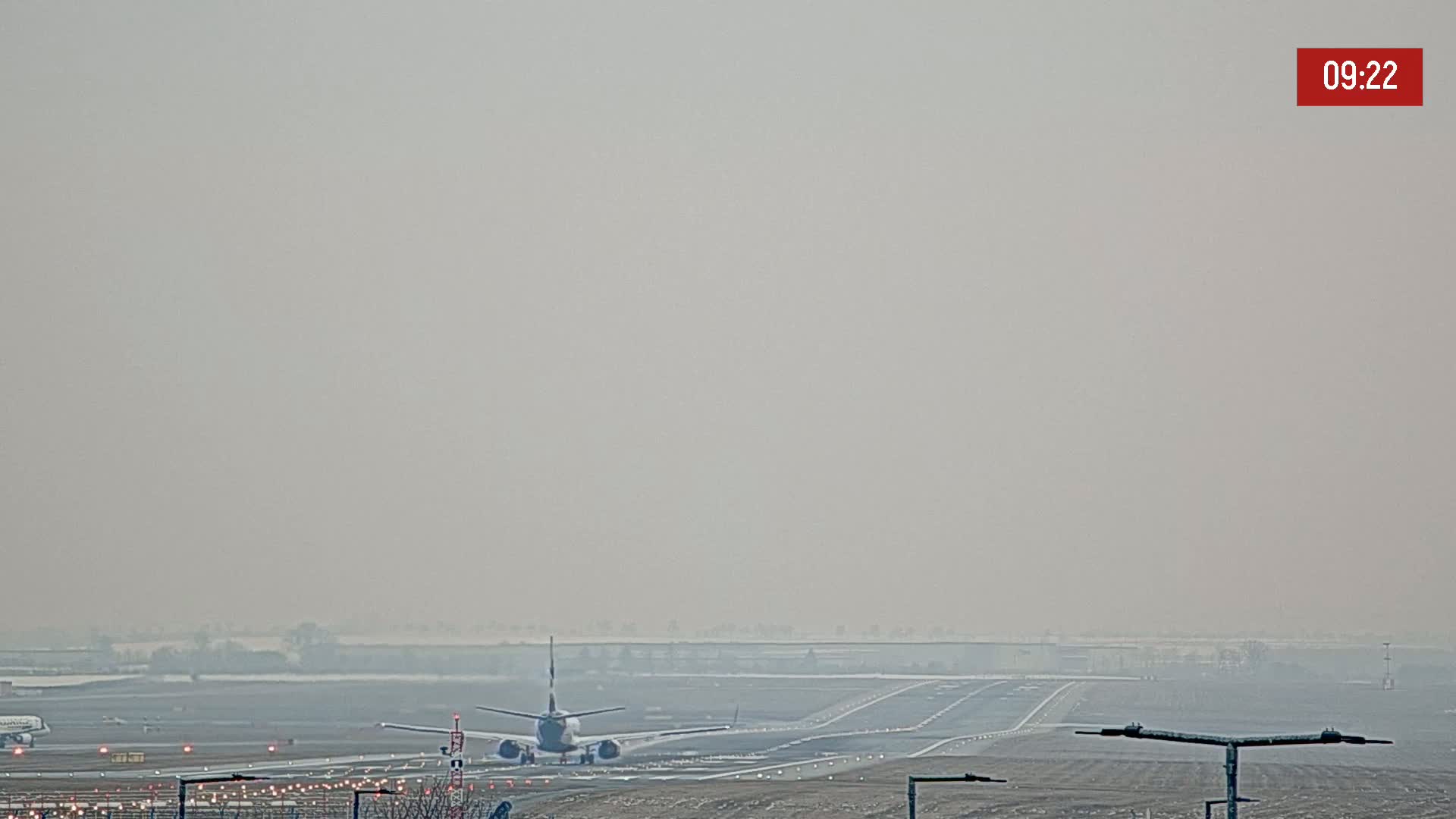A plane taxis on a runway on a hazy day.