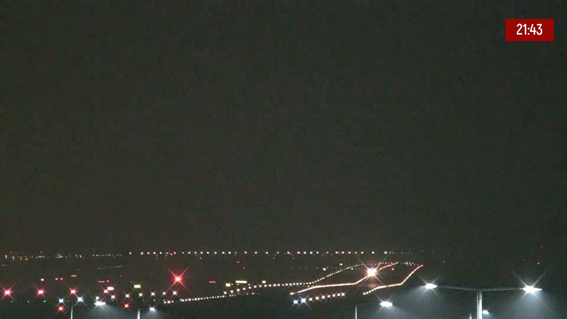 A nighttime view of an airport runway with its lights illuminated under a dark sky.