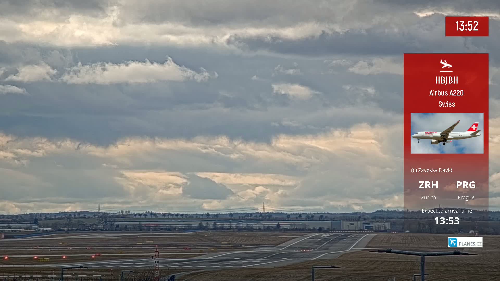 A Swiss Airbus A220 airplane is seen landing on a runway under a partly cloudy sky.