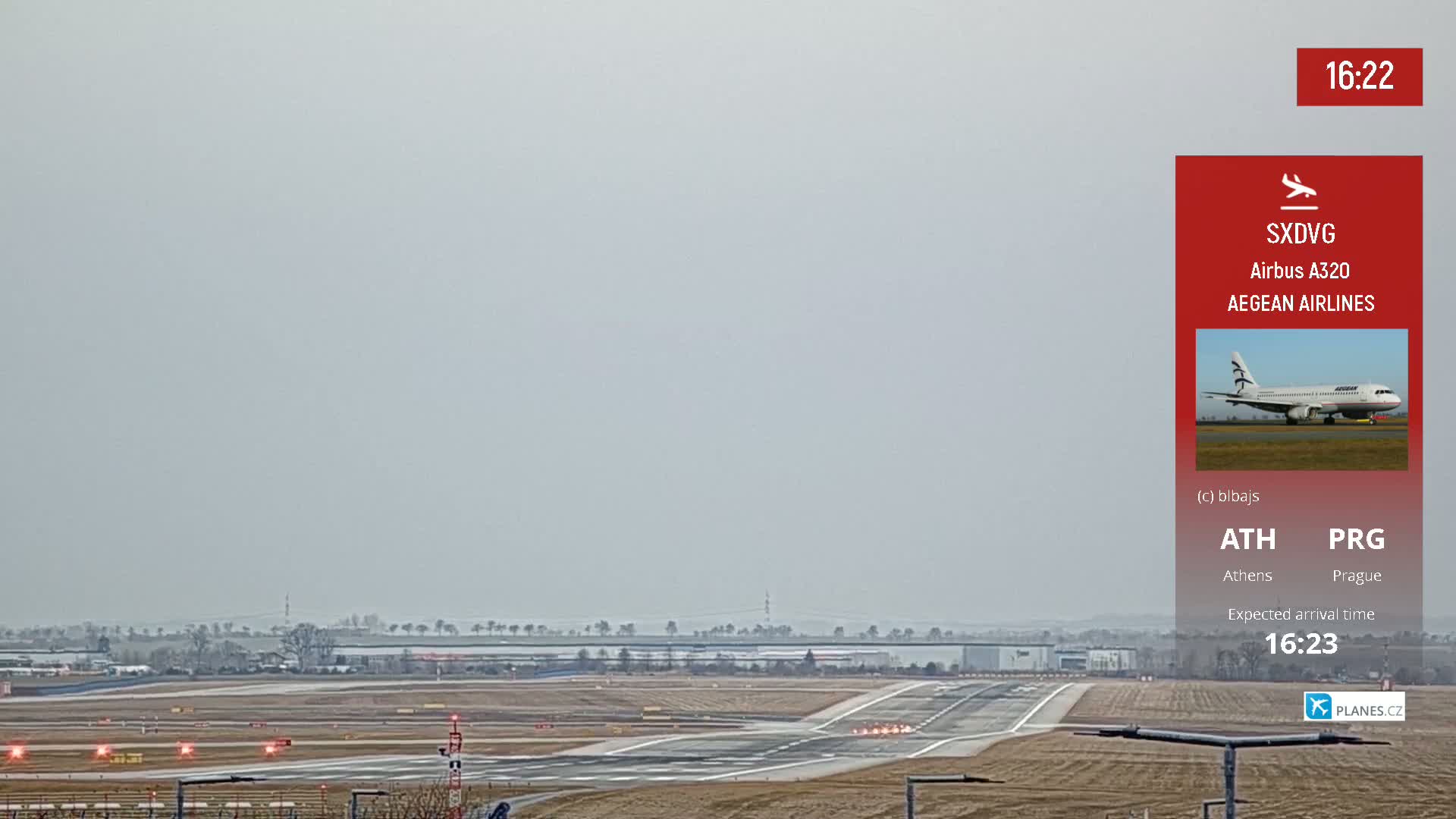An airplane approaches an airport runway under hazy skies.
